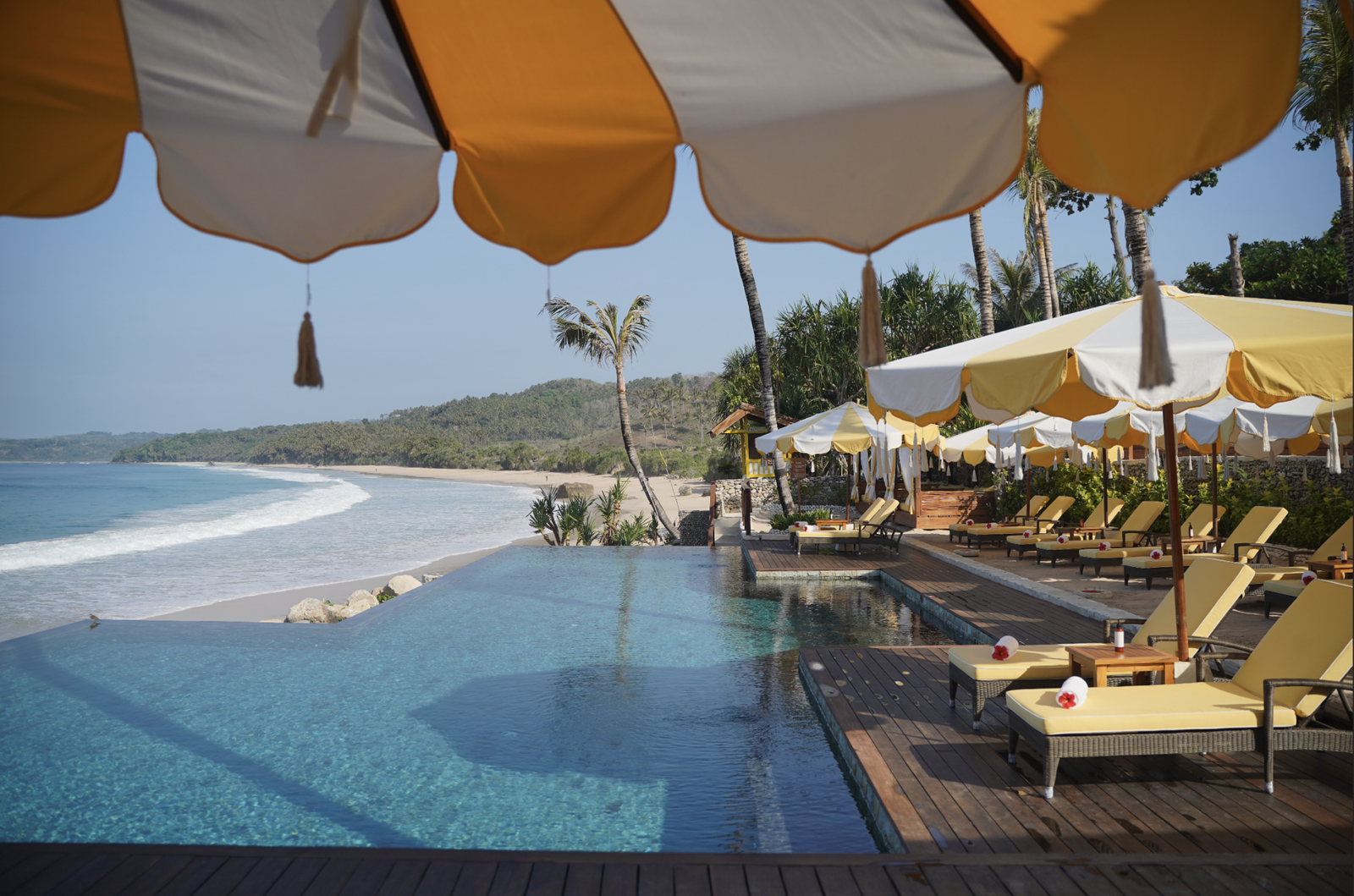 Nihi Sumba infinity pool with yellow loungers overlooking the beach.